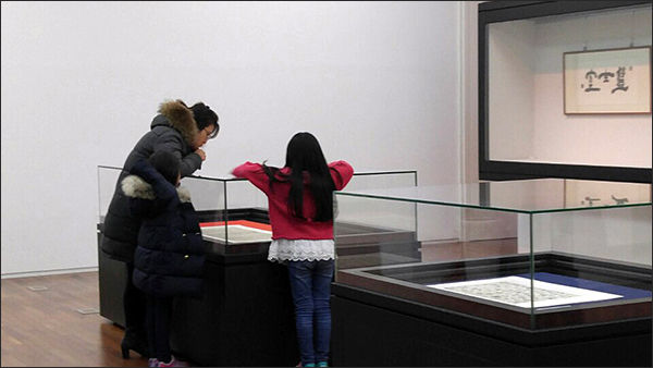 엄마와 아이가 유물을 유심히 들여다보고 있다.