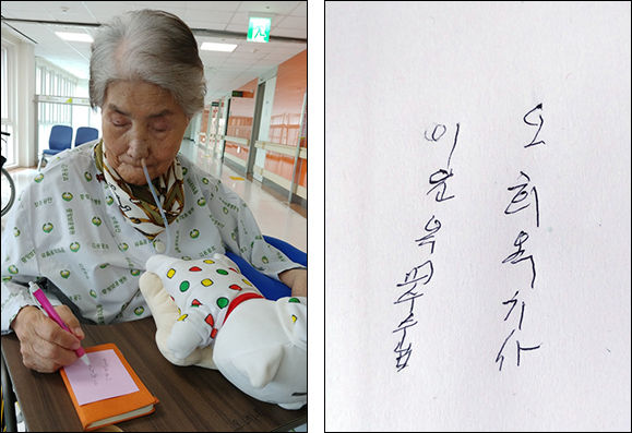 오희옥 지사가 기자의 이름과 자신의 이름을 또박또박 쓰고 있다. 현재 오른쪽은 쓸수 있으나 왼쪽 손은 마비가 온 상태다.(왼쪽), “이윤옥 교수님, 오희옥 지사”라고 오희옥 지사가 또박또박 쓴 글씨
