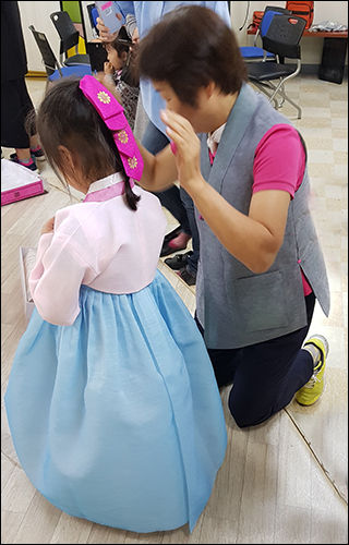 우리옷나누미 관계자가 저소득가정 아이에게 한복을 전달하고 입는 것을 도와주고 있다.