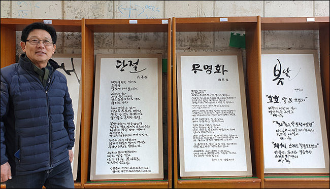 김신홍 작가가 중국시인들이 보내온 시를 쓴 수묵캘리그라피 작품들 앞에 서 있다.