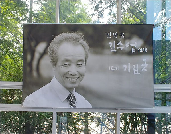 '우리말 사랑을 실천한 김수업 선생 1주기 기림굿'이 열린 경남과학기술대학 본관 2층 대강당 로비에 걸린 김수업 선생 사진. 사진 속에서 선생은 온화한 모습으로 웃고 있다.