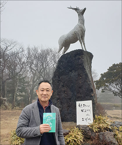 고명주 시인의 첫시집 《한라에서 백두까지 그리고 그 너머》을 김유 작가가 들고 있다.