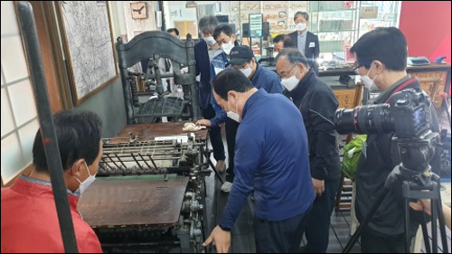 활판인쇄기를 보고 있는 장인들