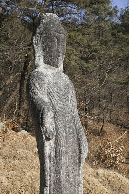 석불의 상세 모습, 옷주름이 타원형으로 겹겹이 늘어진 모습의 통견이며, 양쪽 어깨를 모두 법의로 감싸고 있는 모습이 시대적 양식을 잘 알 수 있다.또, 부처님의 얼굴(상호)은 온화한 인상이고, 귀의 길이가 특히 길게 표현되었으며, 머리는 육계(불룩하게 올라간 모습)이나 나발(소라 모양의 머리카락)이 없다.