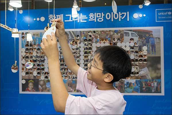청와대 춘추관 로비에서 진행 중인 유니세프 한국위원회 ‘함께 그리는 희망 이야기’ 특별전의 희망 트리에 서울 흥인초 4학년 장주원 학생이 희망 메시지를 걸고 있다. (사진제공=유니세프 한국위원회)