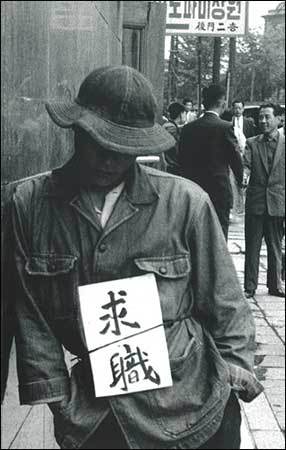 구직 1953년, 서울 명동(직장을 구한다는 뜻을 알리려고 '구직)'이라 적은 종이를 허리춤에 묶고 무표정하게 벽에 비스듬히 기대선 젊은이 그의 모습에서 절망감과 힘겨움이 드러납니다.)