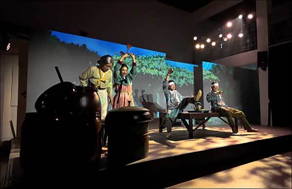 뮤지컬에서 1920년대 삼례의 한 마을, 주인공인 복실(주걱을 들고 있는 소녀)과 할매, 그리고 마을 주민들이 막걸리를 마시며 노래를 부르는 모습